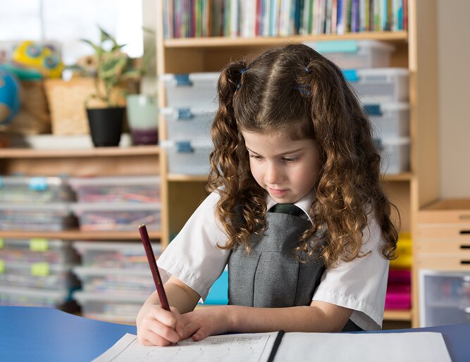 Young student concentrating on her writing at her desk