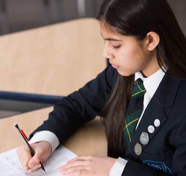Student in KBS uniform writing in her notebook